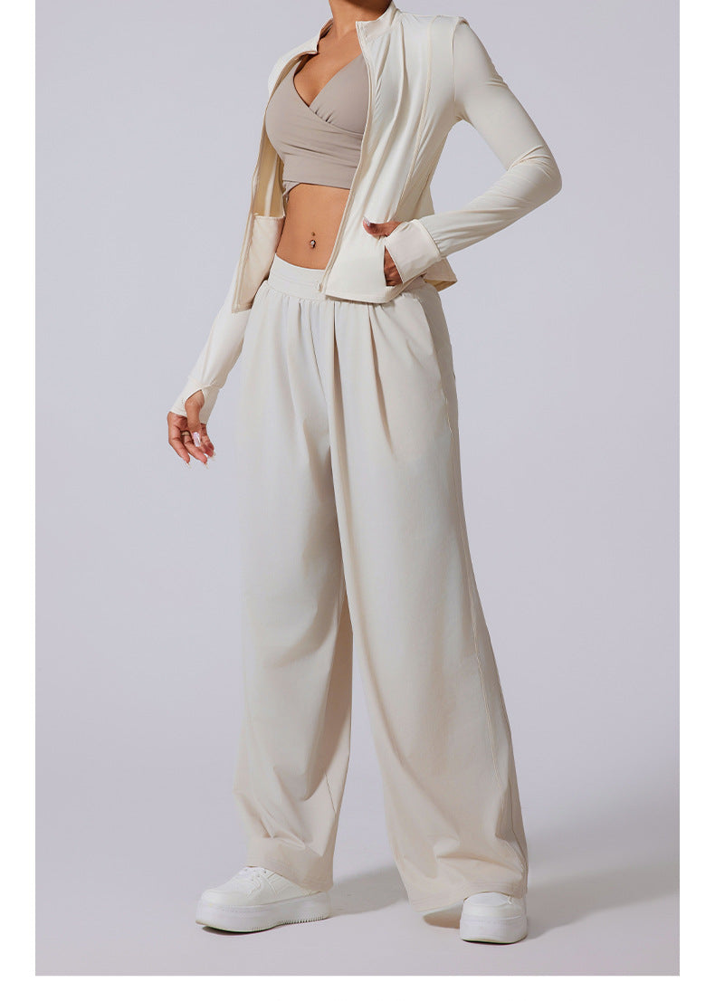 Model wearing ivory jacket, matching wide-leg pants and nude colored crop top with white platform sneakers.