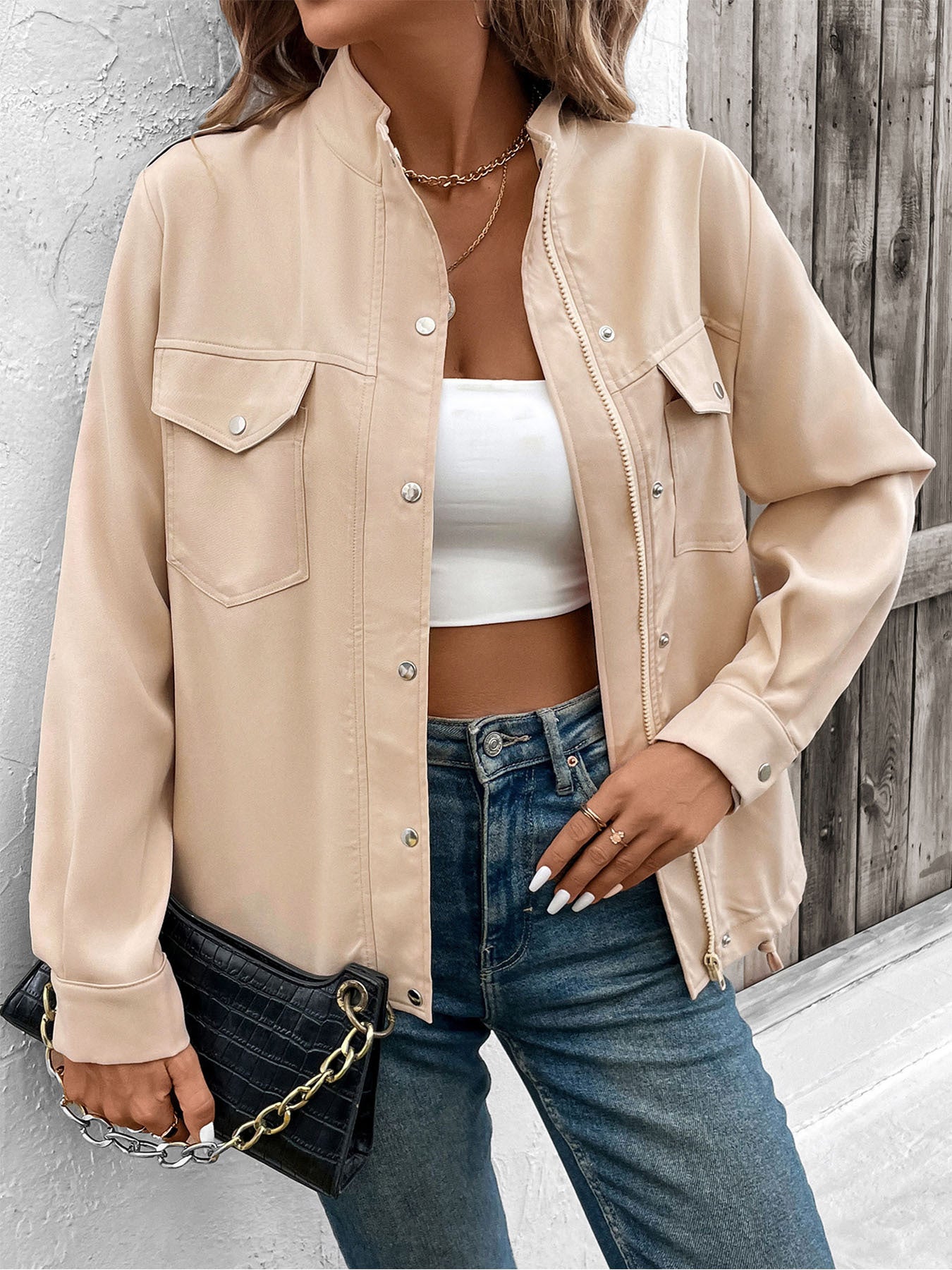 Women's beige utility jacket with front pockets and button details, styled casually with crop top