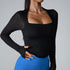 Woman posing in black textured square-neck bodysuit with long sleeves paired with bright blue high-waisted leggings