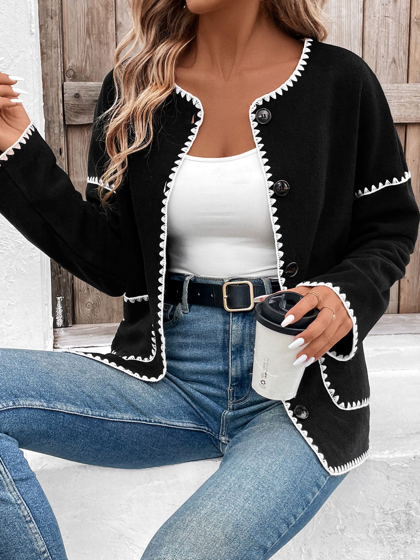 Women's black cardigan with white contrast stitching detail and front pockets