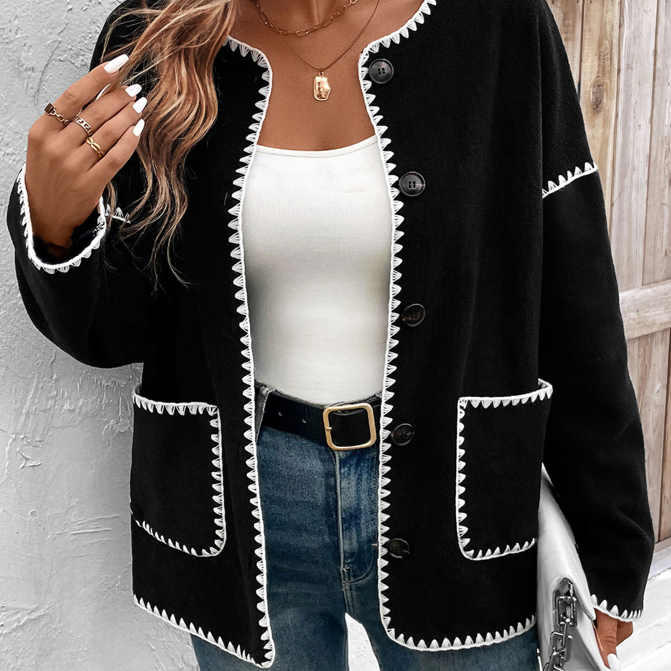 Women's black cardigan with white contrast stitching detail and front pockets
