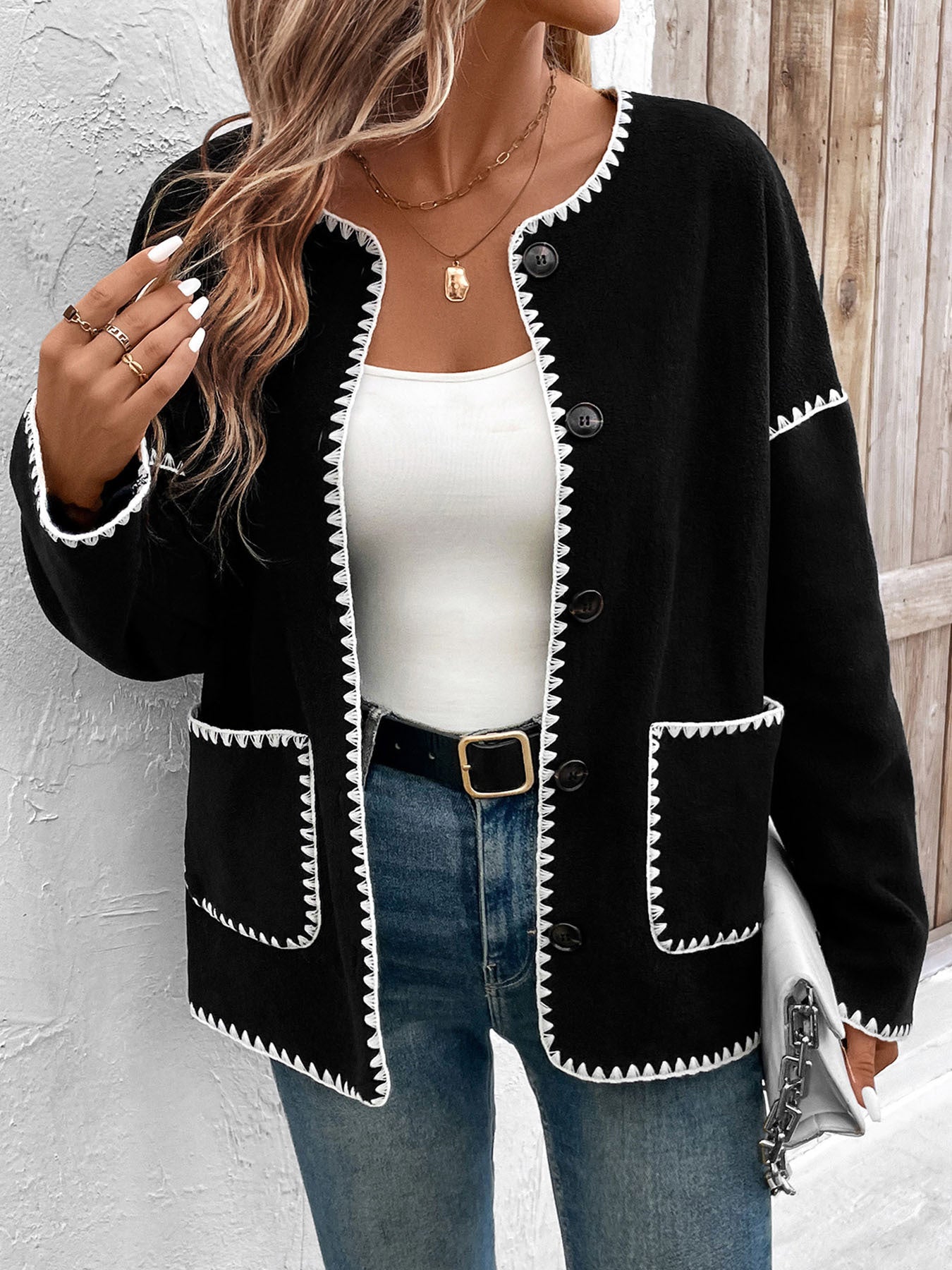Women's black cardigan with white contrast stitching detail and front pockets