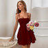 Woman in a deep red tiered mini dress with thin straps, holding a bouquet of pastel roses in a sophisticated indoor setting