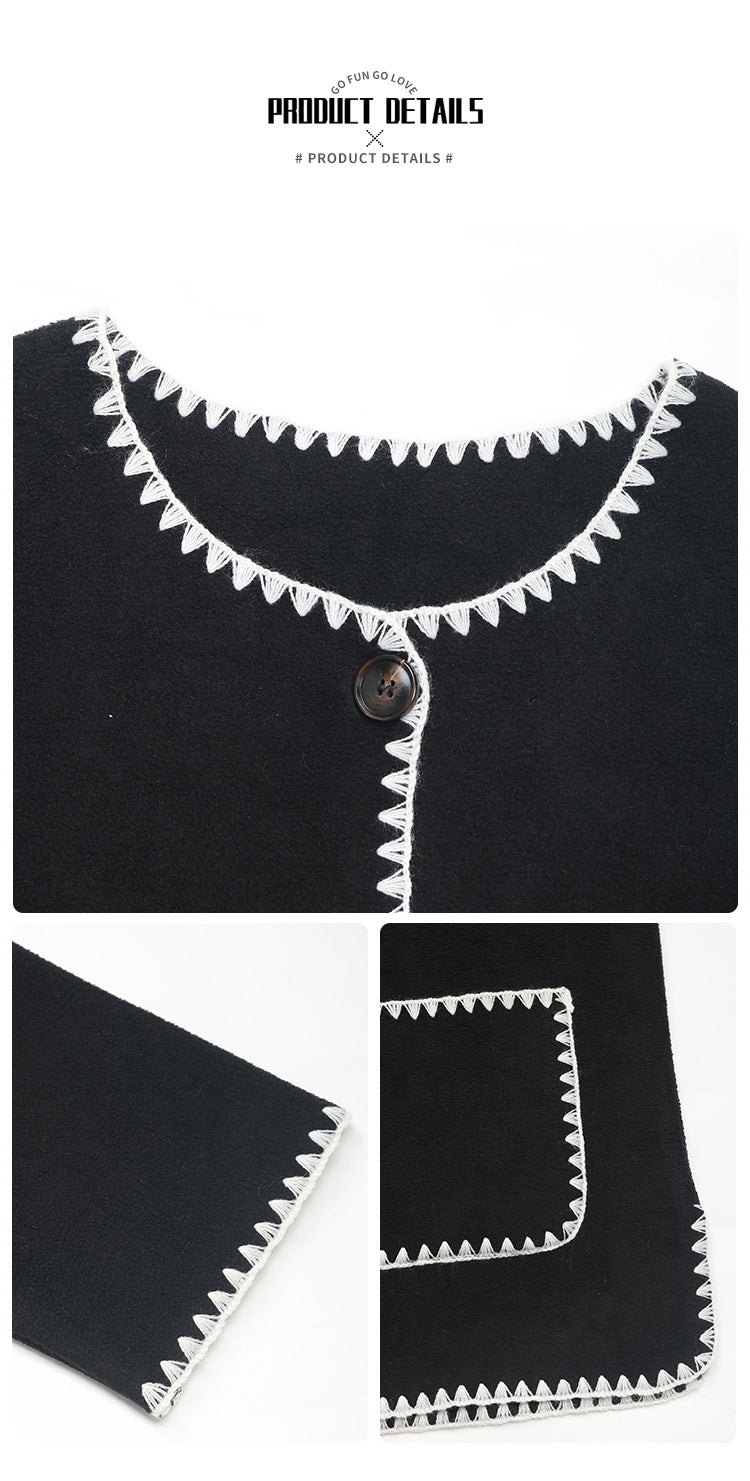 Close-up details of black cardigan showing decorative white contrast stitching and button closure