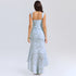 A model is showing the back view of a light blue textured gown with ruched detailing and high-low hemline against a white backdrop