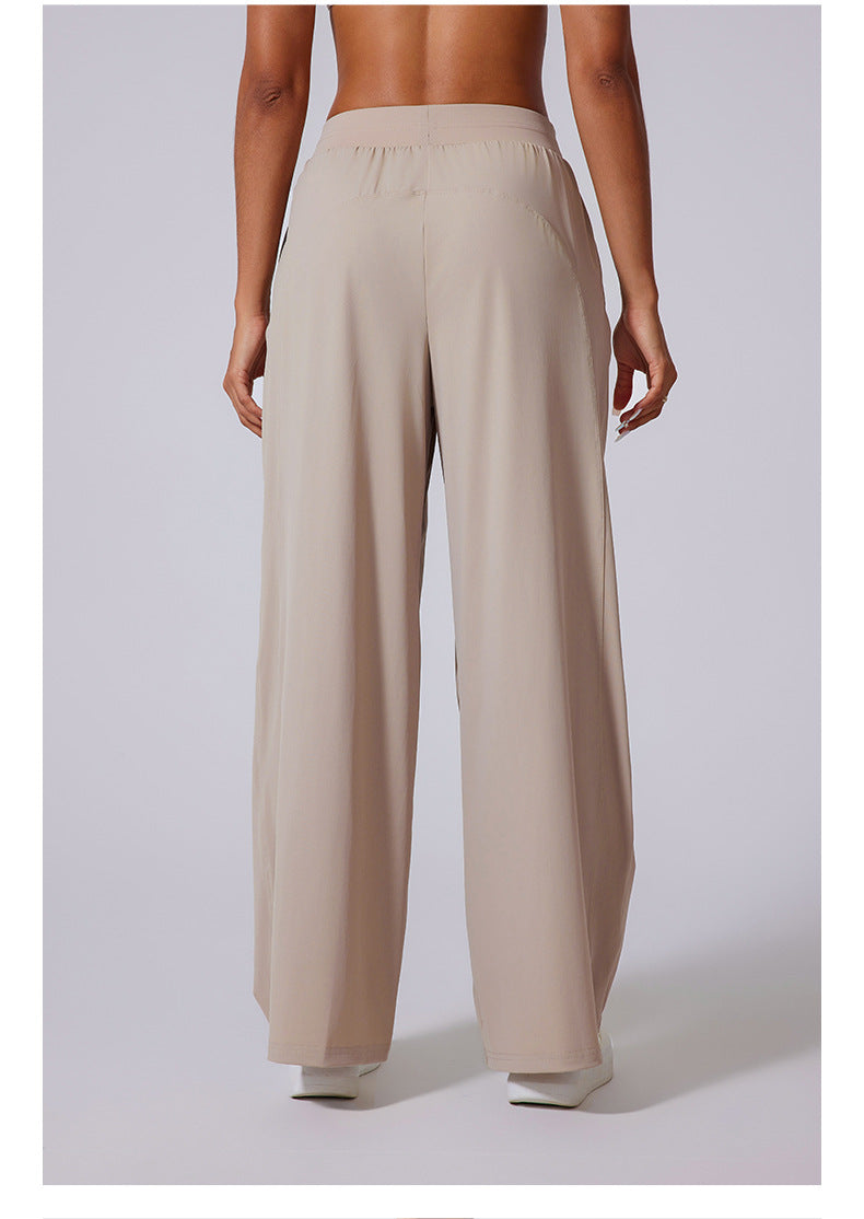 Back view of beige wide-leg lounge pants with elasticated waistband, paired with white crop top and sneakers