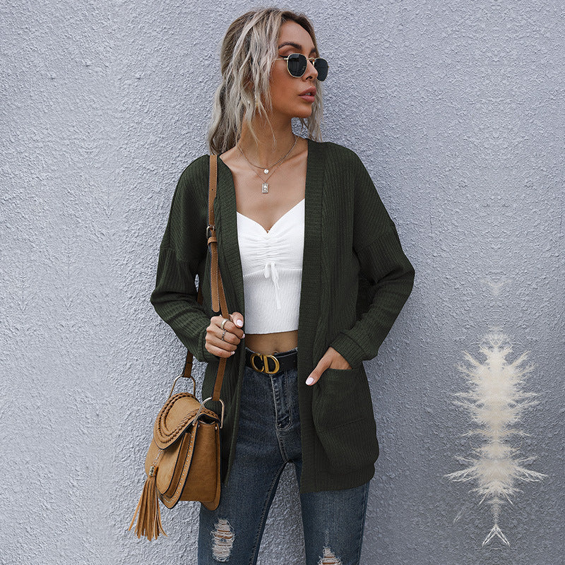 Army green cardigan styled with white top, designer belt, and tan shoulder bag