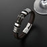 Close-up of a black braided leather bracelet with a gold-tone cross and detailed metal accents.