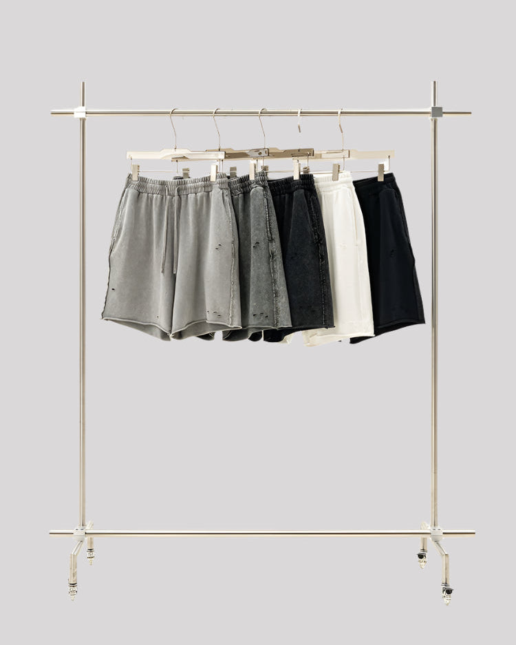 Display rack with five pairs of distressed sweatshorts in gradient colors from light gray to black and white