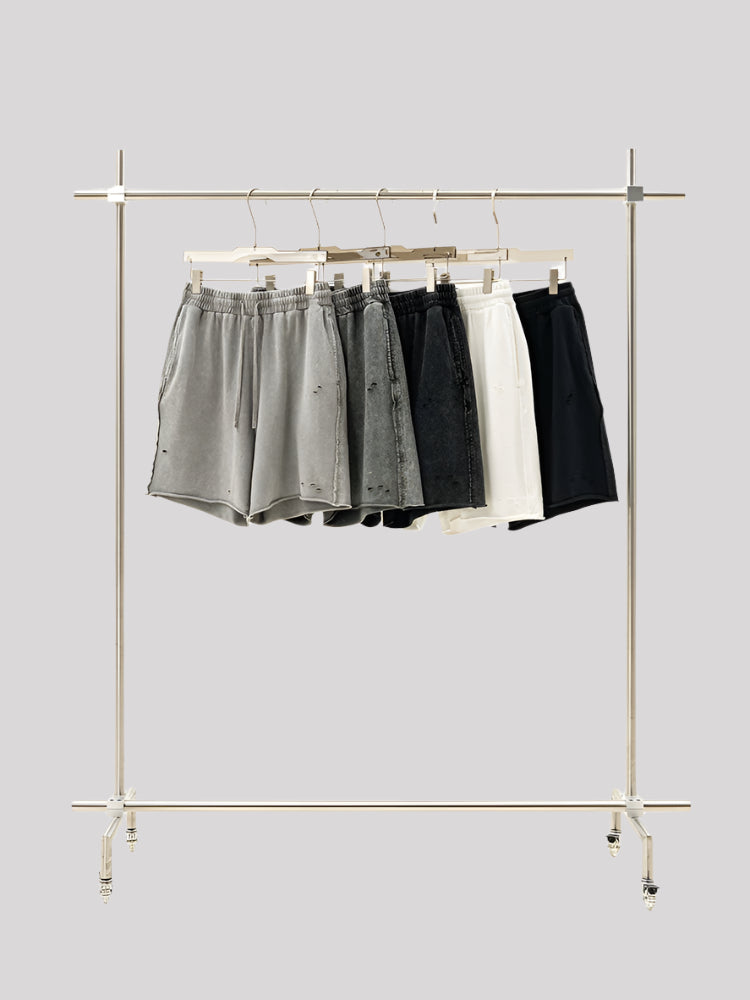 Display rack with five pairs of distressed sweatshorts in gradient colors from light gray to black and white