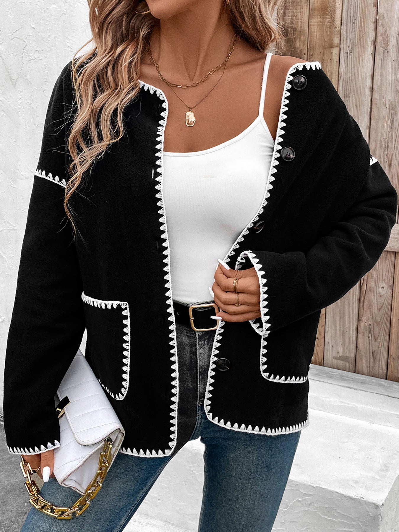 Women's black cardigan with white contrast stitching detail and front pockets