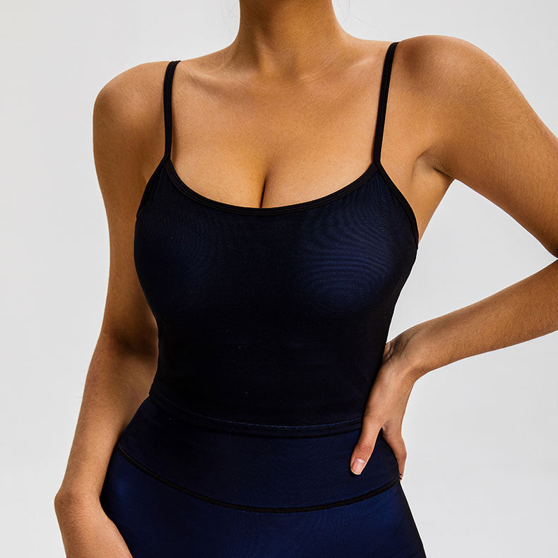 A woman is standing with hand on hip in a navy blue seamless tank top with contoured waistband, showing sculpted athletic silhouette
