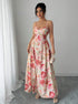 Woman wearing a floral dress standing against a plain background