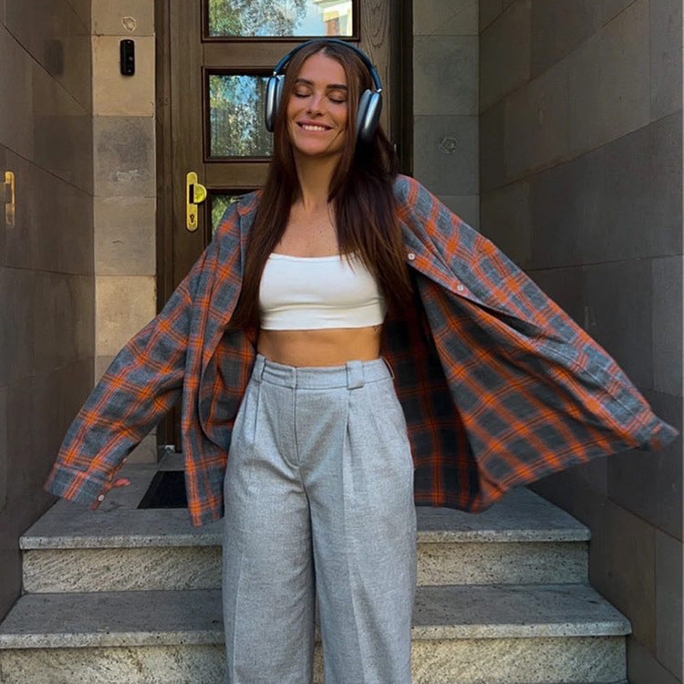 Orange plaid flannel and gray pants, woman wearing headphones on steps
