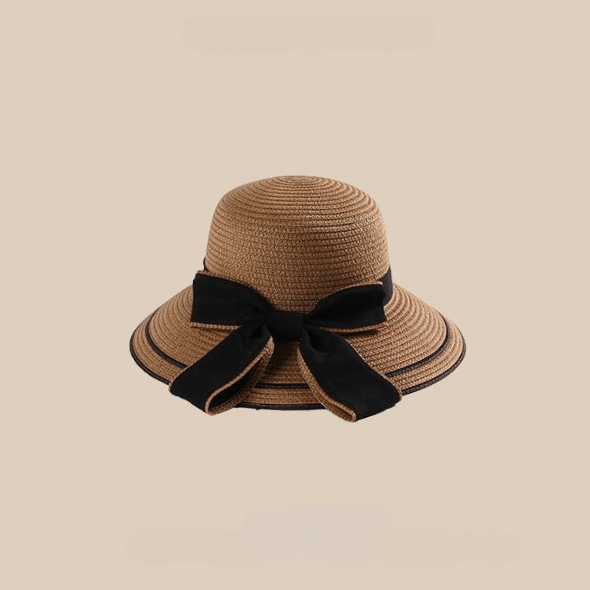 A khaki woven straw sun hat with a wide brim and a large black bow tied at the back, displayed against a beige background.
