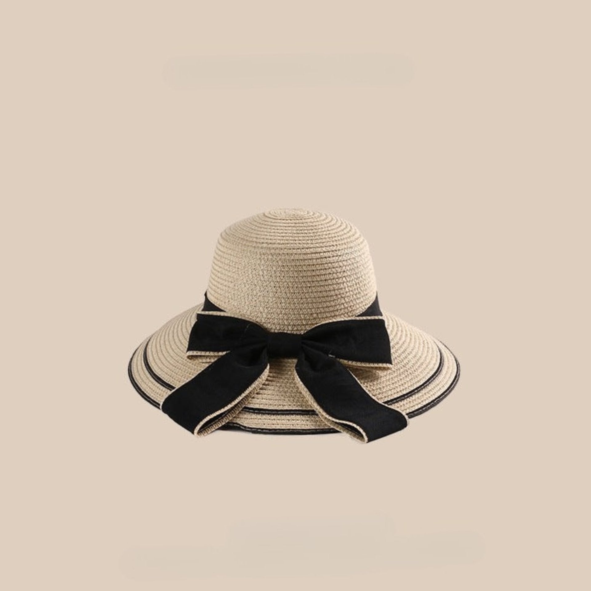 A beige woven straw sun hat featuring a wide brim and a black bow, set against a neutral beige background.