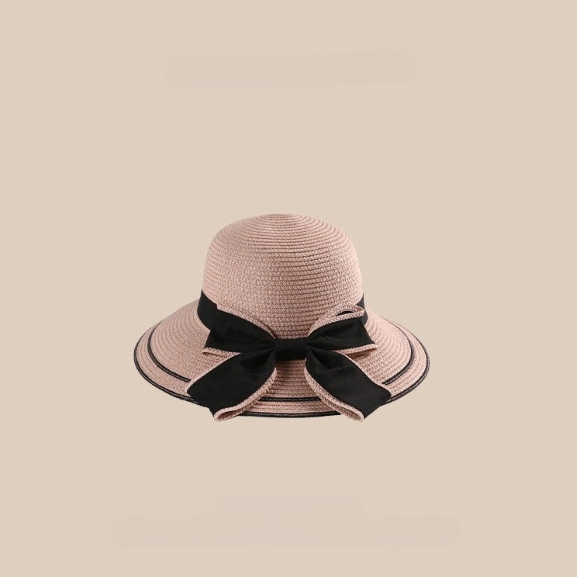 A pink straw sun hat with a black bow detail and a wide brim, displayed against a beige background.