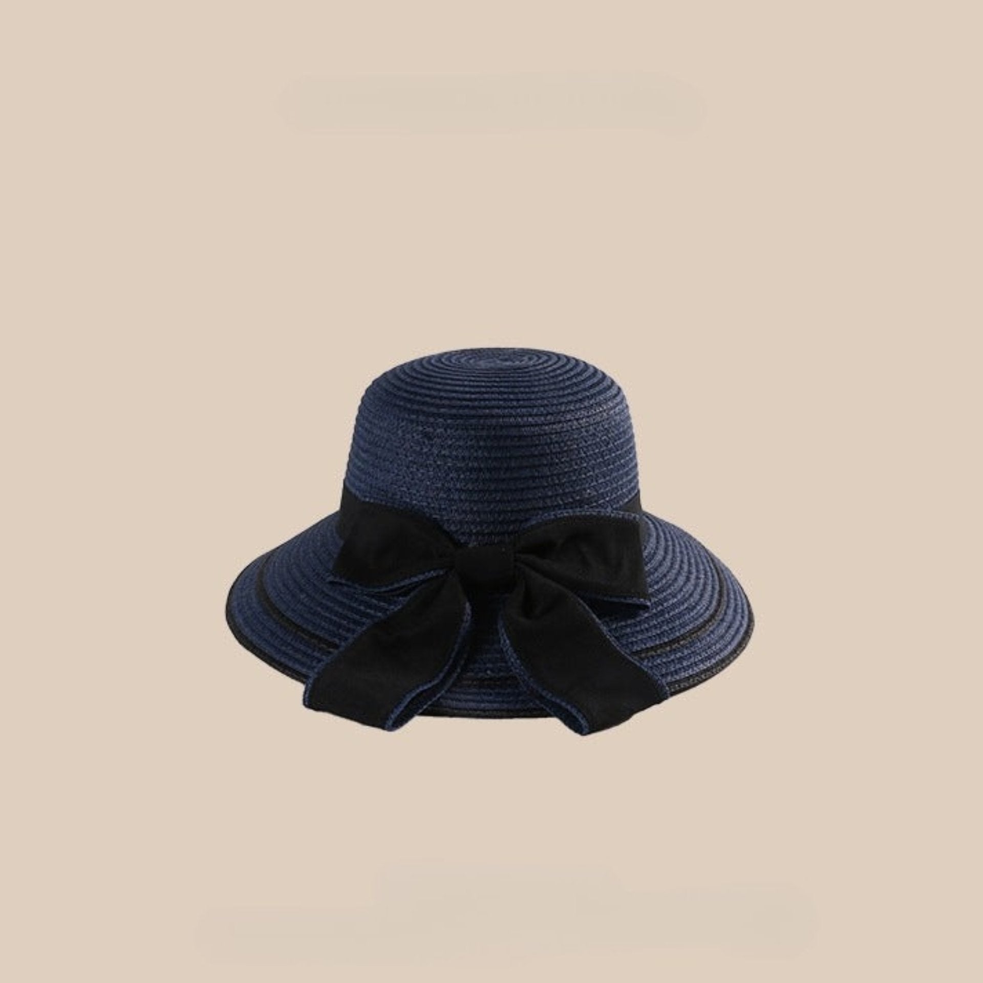 A navy blue woven straw sun hat with a black bow and a wide brim, set against a beige background.