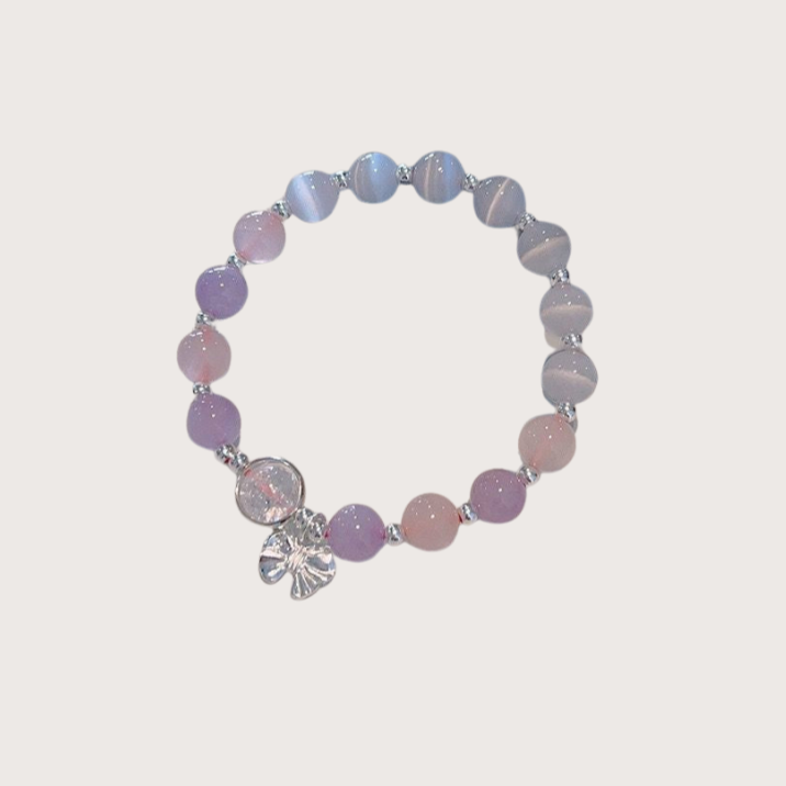 Pastel purple and pink beaded bracelet with silver flower charm, arranged in a circle on a light background.