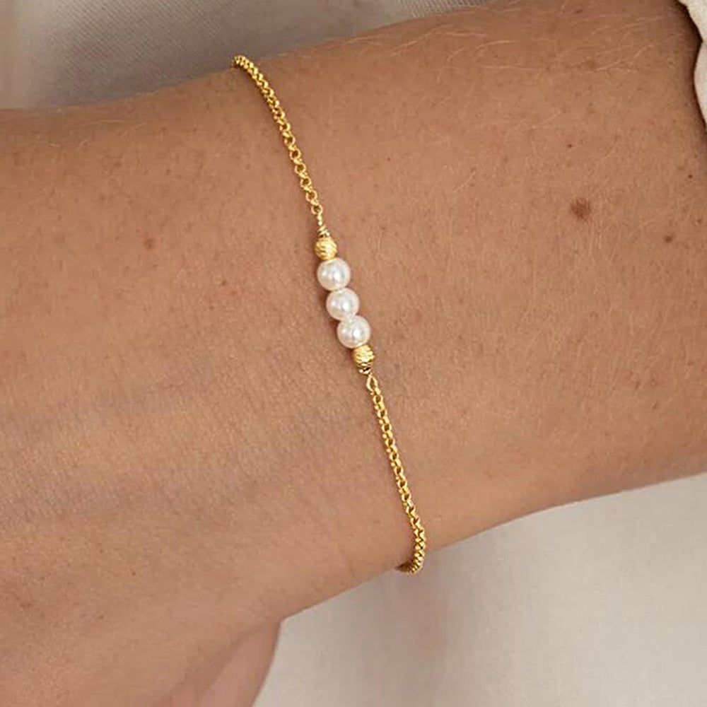 Gold pearl bracelet worn on wrist, showcasing minimalist elegance.