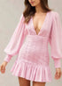 Woman wearing a pink dress with long sleeves.