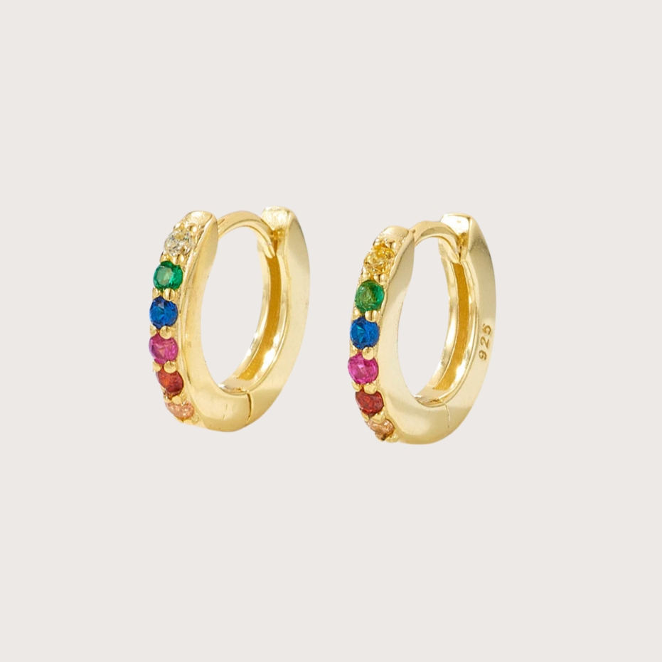 Gold-plated huggie hoop earrings with rainbow cubic zirconia stones, displayed on a white background with soft shadows.