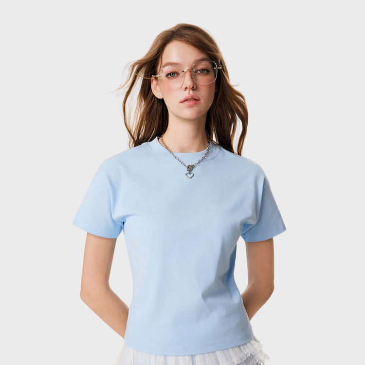 Woman wearing a light blue short-sleeve tee with ruffled mesh hem and silver necklace, styled with glasses.