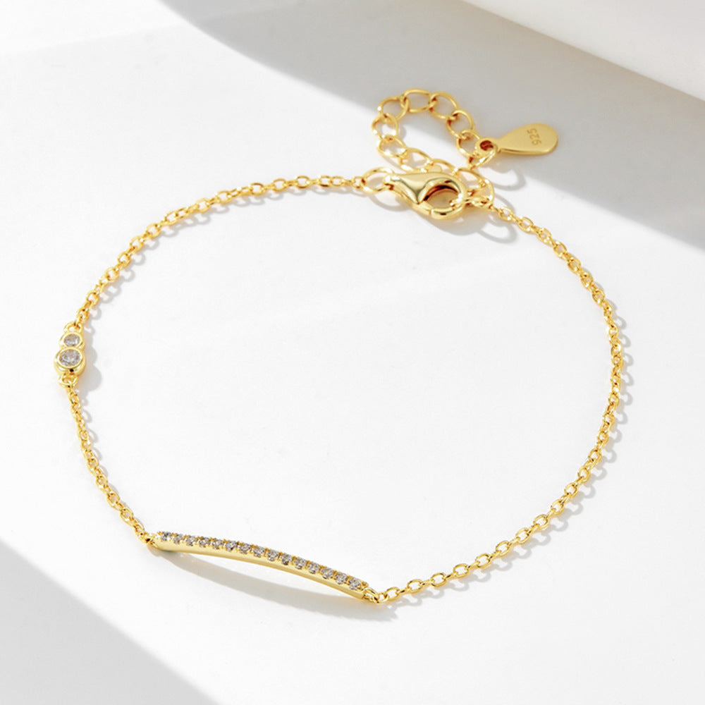 Gold bar bracelet with CZ stones on a white background.