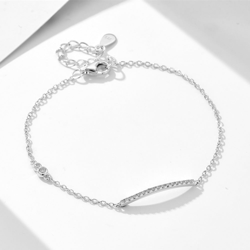Silver bar bracelet with CZ stones, shown on a white surface.
