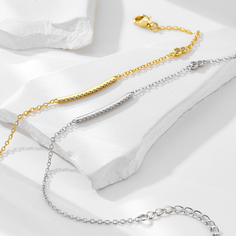 Gold and silver bar bracelets displayed diagonally on white stones.