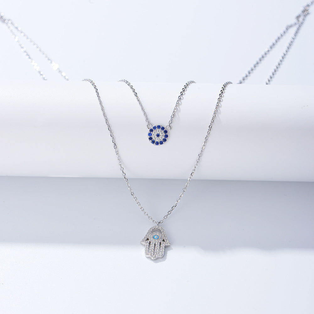 Silver double-layer necklace with blue evil eye charm and Hamsa hand pendant