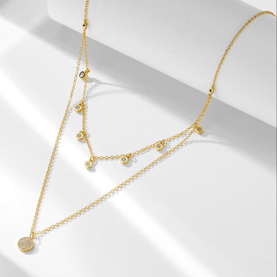 Gold layered CZ choker necklace with pavé disc pendant on white background.