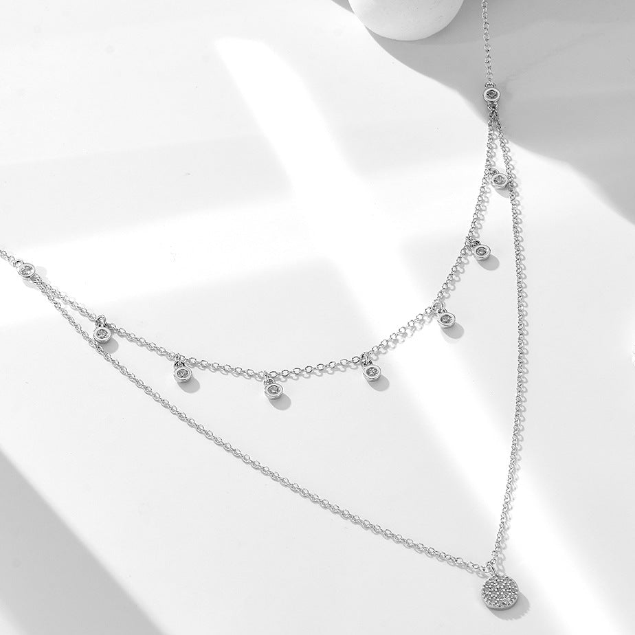Silver double-layer CZ choker necklace with pavé disc charm displayed flat.
