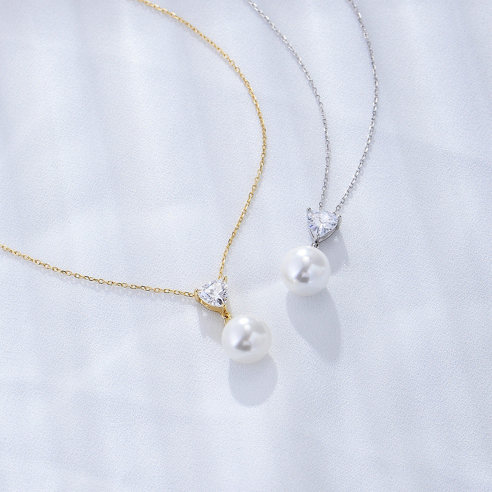 Gold and silver pearl pendant necklaces with heart-cut cubic zirconia stones.