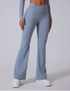 A model wearing powder blue high-waisted flared yoga pants with a seamless design and white platform sneakers on gray background