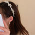 Woman wearing a pearl and crystal floral headband, paired with matching dangling earrings