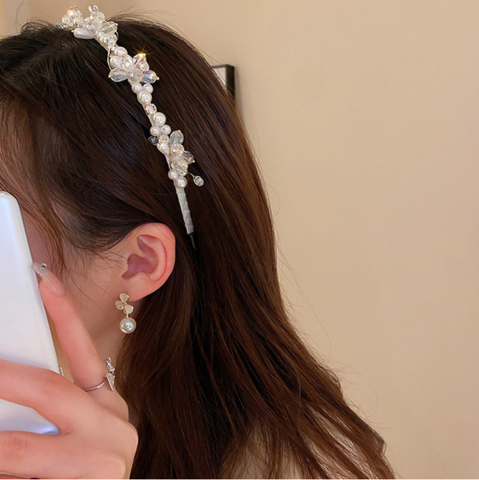 Woman wearing a pearl and crystal floral headband, paired with matching dangling earrings