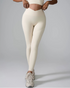 A model wearing cream ribbed high-waisted leggings with matching crop top, standing against gray background