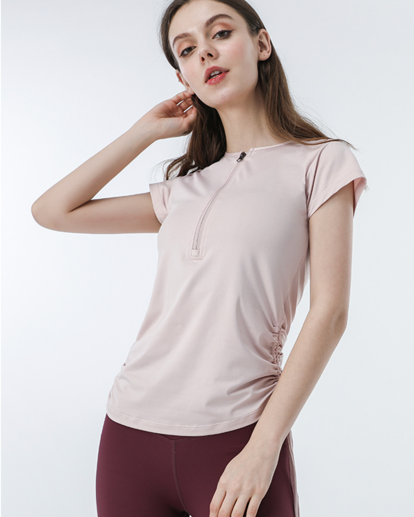 Pink zip-up fitness tee with ruched sides and high-waist burgundy shorts, casual sporty look