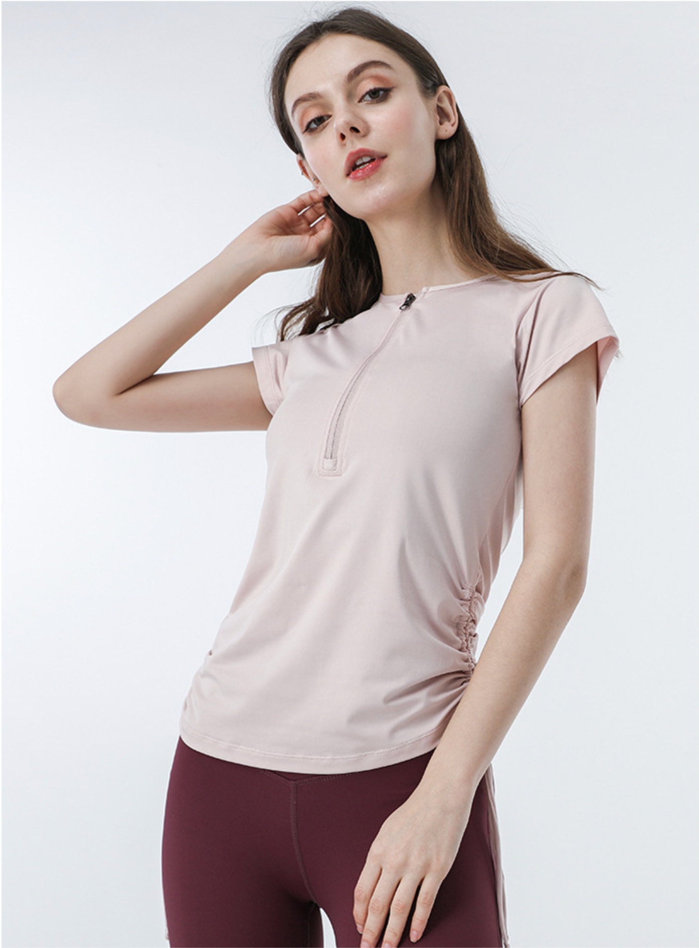 Pink zip-up fitness tee with ruched sides and high-waist burgundy shorts, casual sporty look
