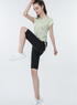 Light green zip-up sports tee with black high-rise shorts, model in active pose
