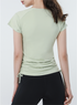 Back view of sage green active tee with ruched drawstring sides, paired with black biker shorts