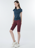 Navy blue ruched active top with burgundy cycling shorts and white sneakers, relaxed pose