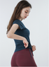 Navy blue ruched sports top with cap sleeves and high-rise burgundy biker shorts, side view pose