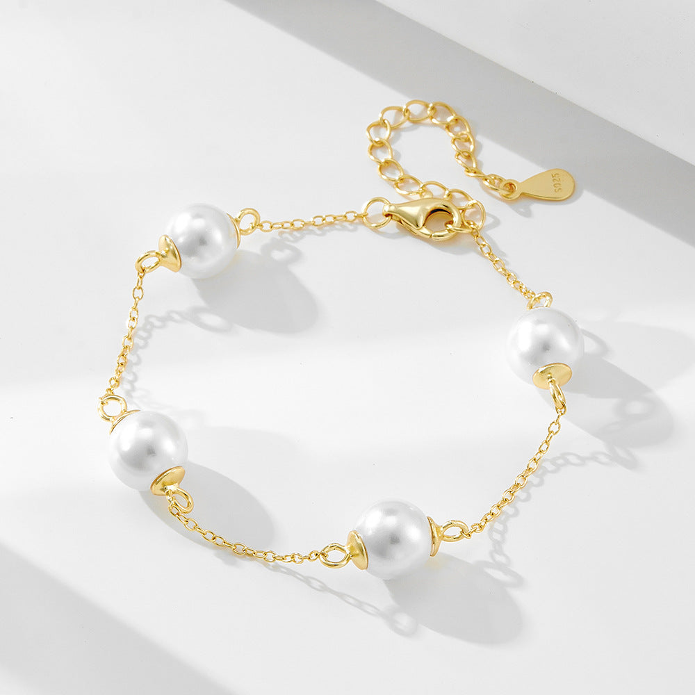 Gold bracelet with five large white pearls spaced evenly along a delicate chain.
