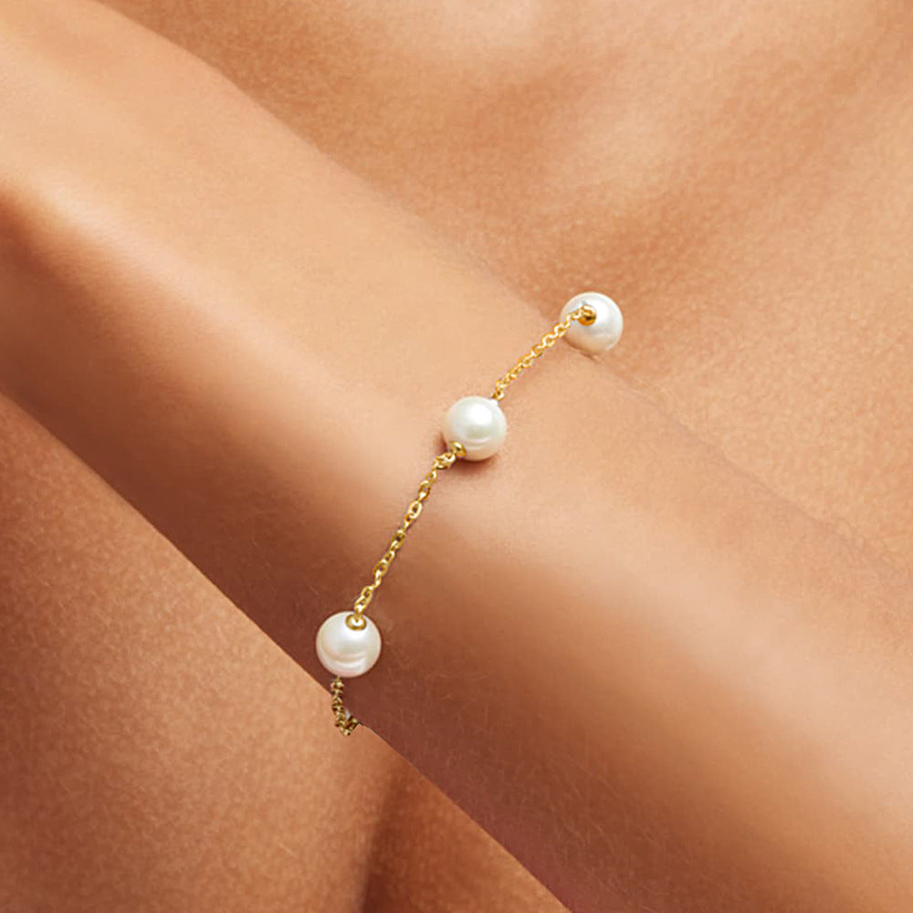 Woman wearing the gold pearl bracelet, showcasing it on her wrist.
