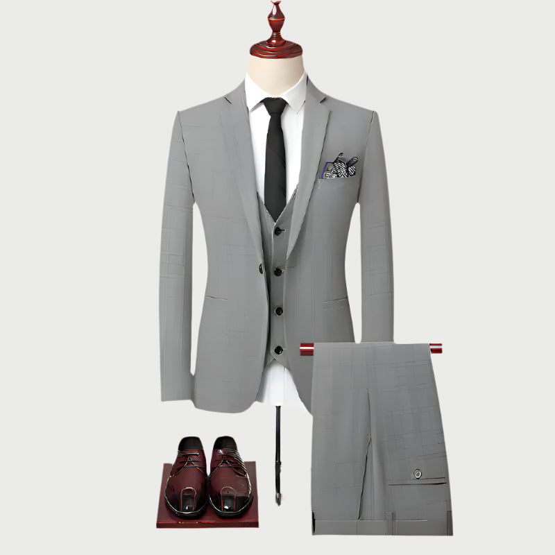 Light gray three-piece suit displayed on mannequin with white shirt, black tie, pocket square, and brown leather dress shoes