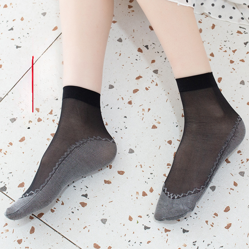 Black sheer ankle socks with ribbed sole detail shown on polka dot background