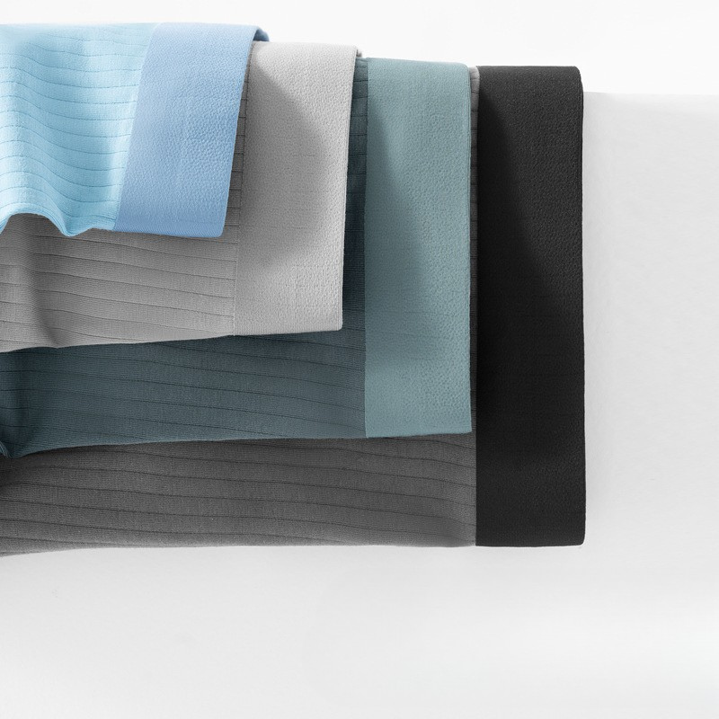 Fabric swatches of men's boxer briefs in multiple colors - light blue, gray, sage, and black with matching elastic waistbands