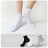 Person wearing white ankle socks with "SPORT" branding, paired with a display of black, white, and gray sock variations